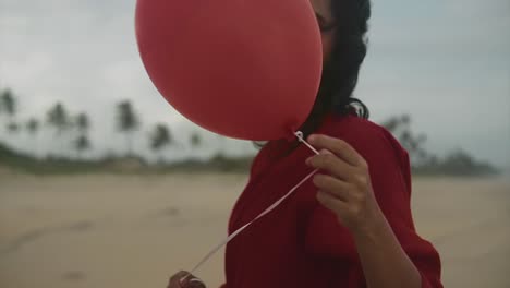 Portrait-of-a-young-beautiful-Indian-woman-holding-a-balloon-in-hand-with-beach-and-palm-trees-in-the-background