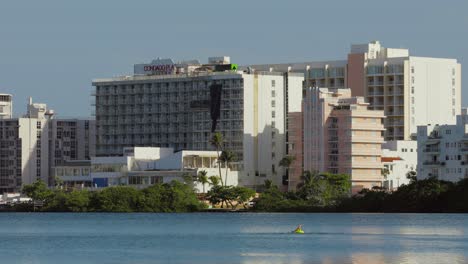 Person-swims-in-open-water-with-Hilton-hotels-and-resorts-of-the-Condado-area-of-the-city-in-the-background---Pan-left