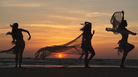 Tres-Damas-Extranjeras-Bailando-En-La-Playa-De-Goa-Con-Actuaciones-Cautivadoras-Y-Manmohan-Posando-Con-La-Puesta-De-Sol-Detrás