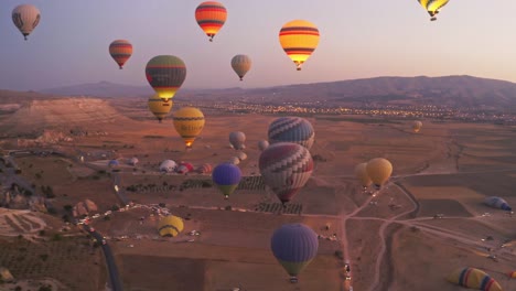 Night-scene-with-these-hot-air-balloons-flying-over-a-valley-in-Cappadocia-Turkey-with-an-aerial-drone-camera-moving-through-them