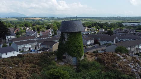 Melin-Wynt-Y-Craig-disused-Llangefni-windmill-ivy-covered-hillside-landmark-aerial-view-orbiting-Welsh-hilltop-mill