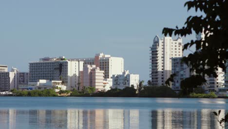 Vista-Panorámica-De-La-Laguna-Del-Condado-Con-Los-Hoteles-Hilton,-Resorts-Y-El-Puente-Dos-Hermanos-Del-área-Al-Fondo---Panorámica-Hacia-La-Izquierda