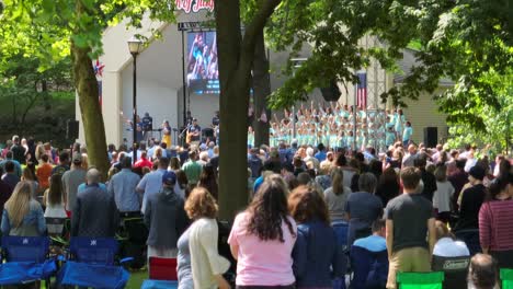 Coro-De-Niños-De-La-Iglesia-Actuando-En-Un-Parque-De-La-Ciudad-Frente-A-Una-Pequeña-Comunidad-En-Un-Día-Claro,-Soleado-Y-De-Verano