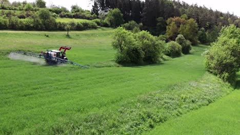 A-farm-worker-drives-tractor-in-a-green-field-spraying-chemicals-down