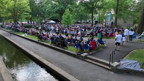 Slow-motion-footage-of-a-gathering-in-a-community-park-to-watch-a-performance-in-the-park-amphitheater-with-many-onlookers