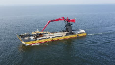 Yellow-barge-BIG-PARTNER-loaded-with-tracked-harbour-material-handling-cranes-being-towed-across-ocean