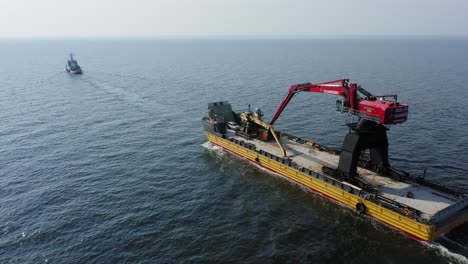 Tug-boat-VARMA-travelling-across-the-open-ocean-pulling-yellow-barge-BIG-PARTNER-loaded-with-tracked-harbour-material-handling-cranes