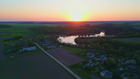 Bird's-eye-view-of-a-sunset-over-a-green-landscape-with-a-village-on-the-river