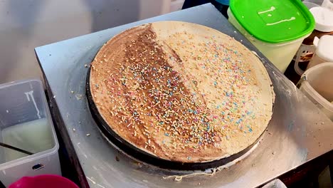 Sweet-freshly-cooked-crepe-with-sprinkles,-close-up-view