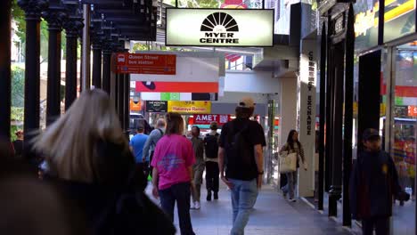 Dynamic-zoom-in-shot-capturing-busy-downtown-street-views-of-Queen-street-mall-crowded-with-people,-Myer-Brisbane-closing-down-sale-located-at-namesake-shopping-centre-at-the-central-business-district