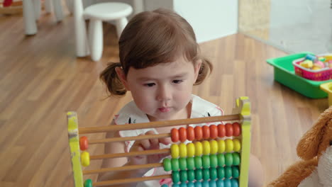 Little-Girl-with-a-Toy-Counting-on-Abacus---Moves-Colorful-Beads-on-Wooden-Rods