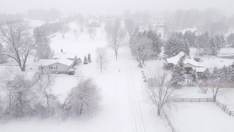Small-American-town-covered-in-deep-layer-of-snow-during-blizzard,-aerial-view