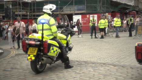 A-police-officer-sits-on-a-bike,-providing-security-for-the-upcoming-pride-march-at-Royal-Mile-in-Edinburgh,-ensuring-the-safety-and-protection-of-the-LGBTQ+-community