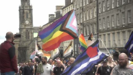 Witness-a-lively-scene-as-people-walk-proudly,-holding-the-pride-flag,-along-the-iconic-Royal-Mile-in-Edinburgh-during-the-vibrant-Pride-march