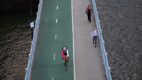Toma-Estática-Que-Captura-La-Actividad-En-El-Carril-Bici-Bicentenario-Junto-Al-Río-Brisbane,-Ciclistas-Andando-En-Bicicleta-Y-Trabajadores-De-Oficina-Fuera-Del-Trabajo-Caminando-Por-El-Camino-A-Casa