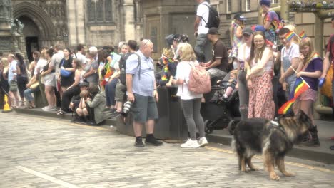 Capture-the-lively-scene-as-people,-including-a-camera-man,-kids,-family,-and-a-dog,-eagerly-wait-at-the-iconic-Royal-Mile-for-the-thrilling-pride-march