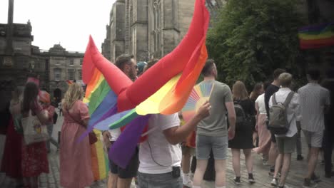 Erleben-Sie-Den-Lebhaften-Geist-Eines-Mannes,-Der-Aufblasbare-Flügel-Trägt,-Die-Mit-Den-Farben-Der-LGBTQ-Flagge-Geschmückt-Sind,-Und-Der-Stolz-Am-Pride-Marsch-Entlang-Der-Berühmten-Royal-Mile-In-Edinburgh-Teilnimmt