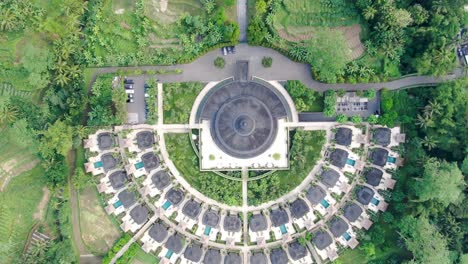 Temple-building-and-luxury-lodges-with-pools-around,-aerial-top-down-view