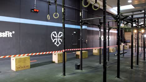 Arena-De-Crossfit-Preparada-Para-Competición:-Barras-De-Dominadas,-Anillas,-Caja-De-Salto-Y-Zona-De-Competición-Marcada-Con-Cinta-Adhesiva.