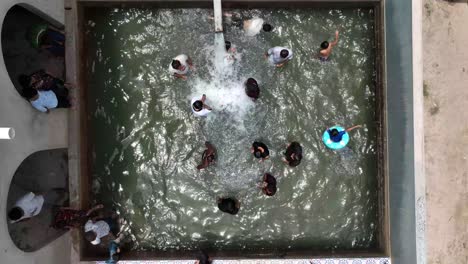 Luftaufnahme-Einer-Gruppe-Männlicher-Freunde,-Die-Im-Ländlichen-Sindh-Einen-Swimmingpool-Genießen