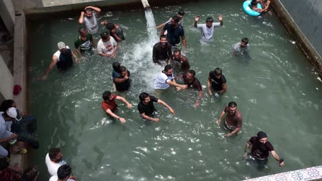 Aerial-View-Of-Male-Friends-Enjoying-Swimming-Pool-In-Rural-Sindh