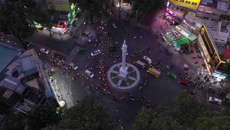 Traffic-roundabout-at-night-from-drone-descending-between-trees