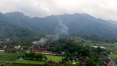 Local-Indonesian-village-with-mountain-range-in-background,-aerial-drone-view