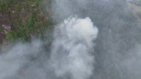Drohne-Fliegt-Durch-Rauch,-Während-Unten-Am-Steilen-Hang-Ein-Frisch-Begonnener-Waldbrand-Brennt