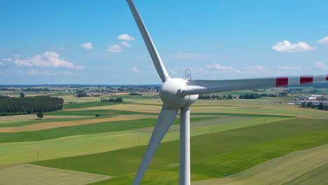 Aerial-close-up-of-rotating-wind-turbine-producing-green-energy-on-countryside-field-during-sunlight