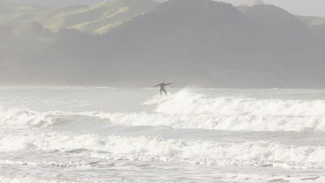 Wide-shot-of-a-man-catching-waves-on-a-sunny-day-in-Castle-Point,-New-Zealand
