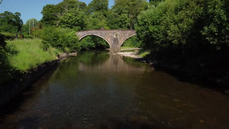 Rising-drone-footage-of-a-man-standing-on-double-arched-bridge-daytime