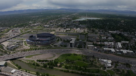 Luftdrohne-In-Der-Innenstadt-Von-Denver,-Filmisch,-Mile-High-Stadion,-Denver-Broncos,-Fußball,-South-Platte-River,-Elitch-Gardens,-Stadtbild-Mit-Ausläufern-Der-Rocky-Mountains,-Colorado,-Autos,-Verkehr,-Sommer,-Kreisen