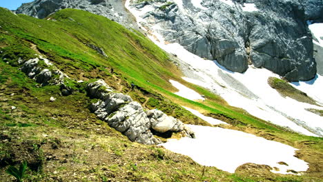 3-Nicht-Wiederzuerkennende-Menschen-Wandern-Den-Hügel-Hinauf,-Mit-Schmelzendem-Schnee-Und-Felsen-An-Der-Seite