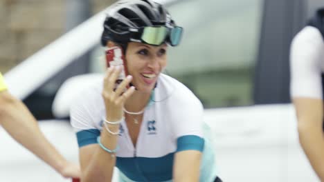 Close-up-of-female-cyclist-wearing-a-racing-cycling-jersey-makes-a-phone-call-and-smiles-while-riding