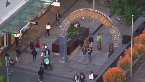 Dynamic-zoom-in-shot-capturing-iconic-landmark-Queen-street-mall-archway-from-above,-bustling-downtown-Brisbane-city-with-people-strolling-at-the-outdoor-shopping-mall