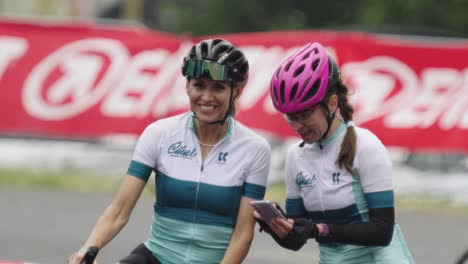 Two-female-cycling-racers-having-fun-over-mobile-phone-photos