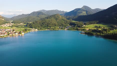 Flyover-aerial-of-light-blue-lake-in-Austria,-Fuschl-am-see,-summer-sunny-day