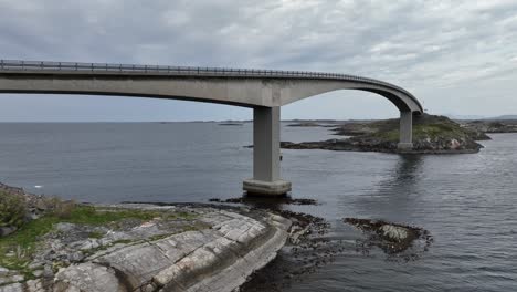 Storseisundet-bridge-along-the-famous-Atlantic-Ocean-Road-in-Norway---Low-altitude-aerial-approaching-bridge-and-ocean-passing-below