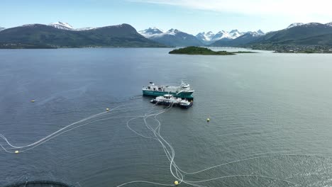 Fjordfrende-Salmon-farm-support-vessel-is-bringing-food-for-the-fish---Salmon-farms-in-Vestnes-close-to-Molde-in-Norway---Aerial