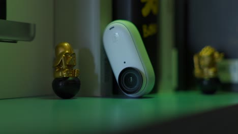 Vista-De-Cerca-De-Insta360-Go-3-Descansando-Sobre-Un-Estante-Bañado-Por-Iluminación-Rgb