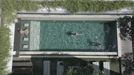Caucasian-tourists-swim-in-sunny-outdoor-pool-in-Bali-tourism-resort