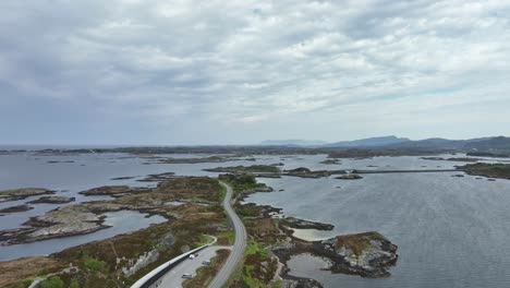 The-Atlantic-Ocean-Road-in-western-Norway---Aerial-moving-forward-above-tourist-visitor-centre-and-cafe-while-looking-North-along-the-cost