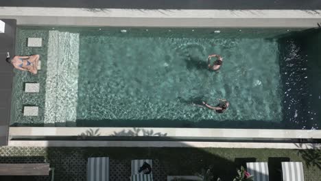 Straight-down-view-of-tourists-enjoying-sunny-outdoor-resort-pool
