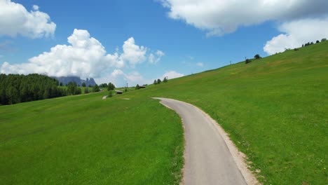 Aerial-drone-follow-shot-of-a-woman-walking-on-a-Seiser-Alm-road-in-Dolomiti,-Italy