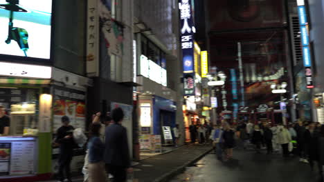 Tokio,-Japan---8.-April-2023:-Menschen,-Die-Bei-Nieseligem-Abend-Im-Einkaufsviertel-Von-Shibuya-Spazieren-Gehen