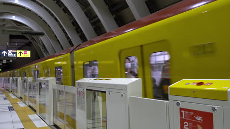 TOKYO,-JAPAN---APRIL-8,-2023:-Train-approaching-Tokyo-Shibuya-station-platform-with-M-shaped-white-ceiling
