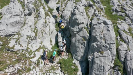Drone-slowly-flying-towards-group-of-kids-climbing-up-a-steep-mountain-ledge