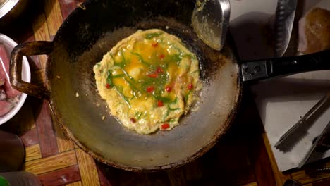 Cocina-Deliciosa-Tortilla-De-Huevo-En-Una-Sartén-Caliente-Con-Aceite-De-Cocina-En-Chinatown,-Bangkok,-Tailandia---Vista-Superior