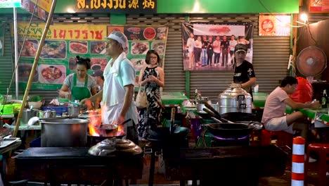 A-Thai-Man-Lit-Up-The-Fire-In-The-Stove-In-A-Food-Stall-In-Chinatown,-Bangkok,-Thailand---wide-shot