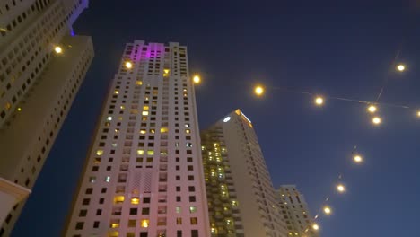 Malerische-Aussicht-Auf-Hochhäuser-In-Der-Jumeirah-Beach-Residence-In-Dubai,-Vereinigte-Arabische-Emirate-Bei-Nacht-–-Kreisende-Aufnahme-Aus-Niedrigem-Winkel